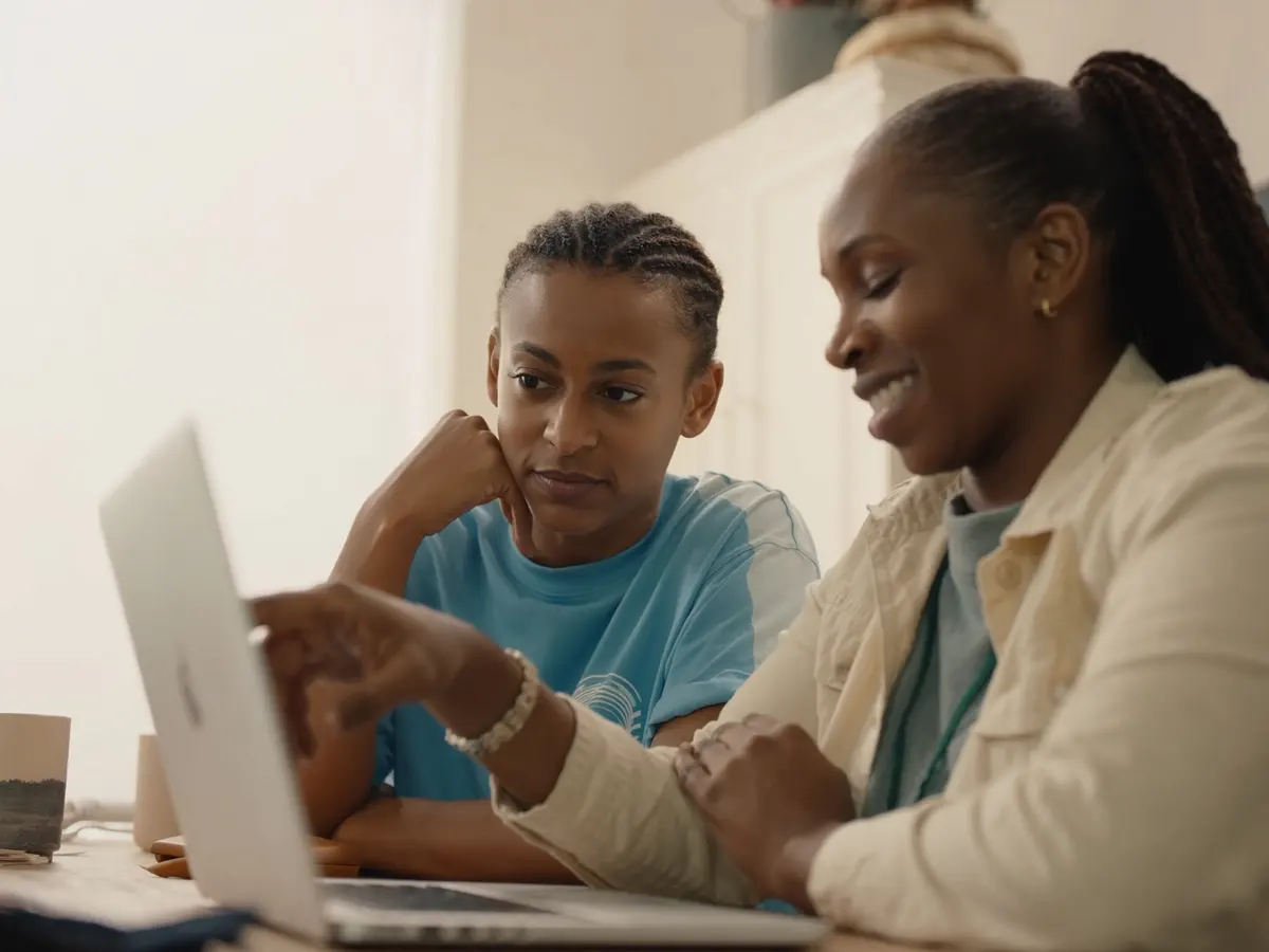 Two people reviewing something together on a laptop, one pointing at the screen